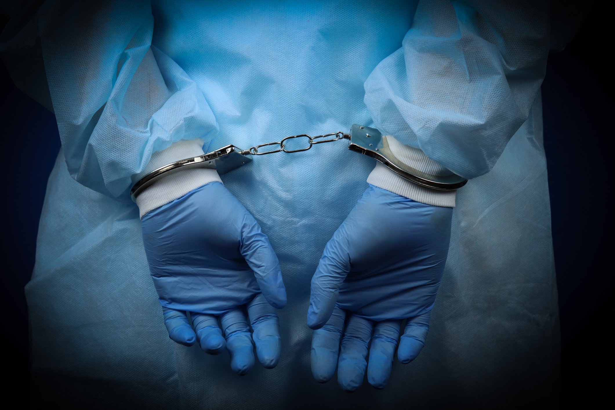 Doctor in scrubs handcuffed behind back